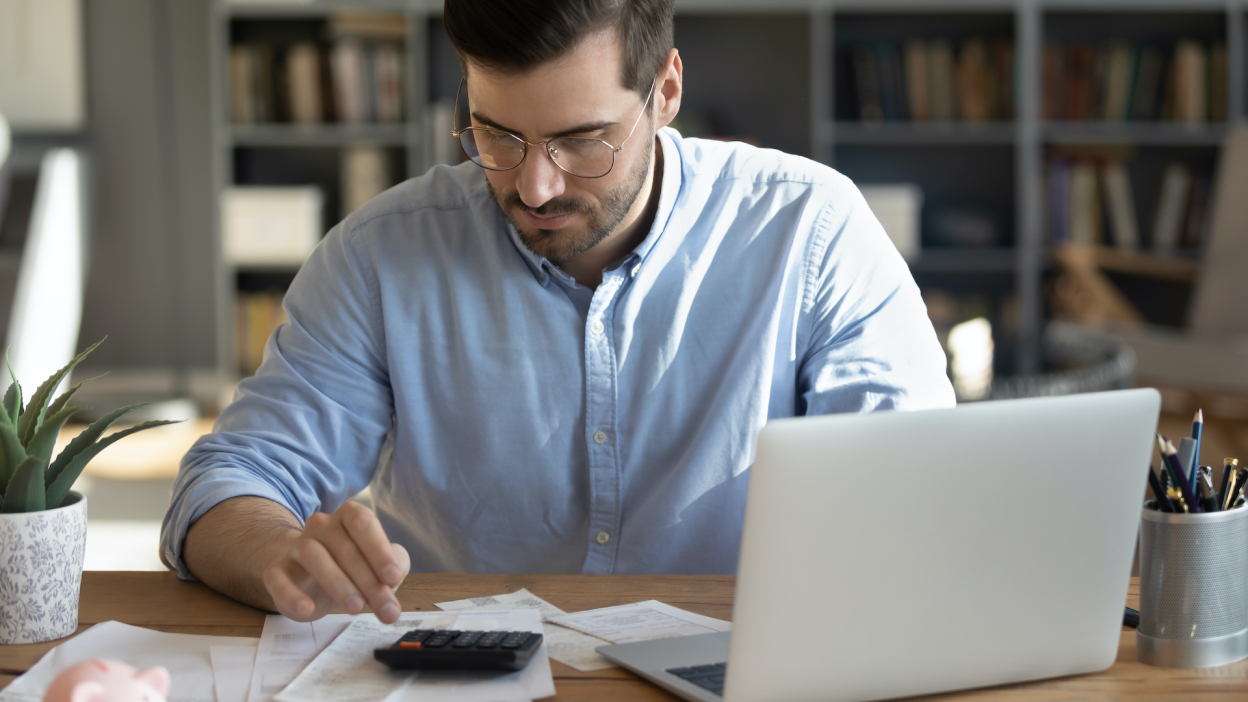 man looking at accounts on computer and using calculator