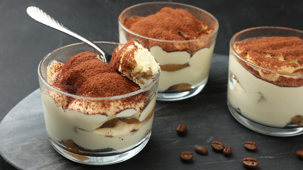 Three cups of tiramisu on a table.