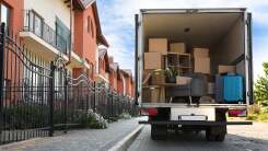 A partially loaded moving truck sits outside an apartment building