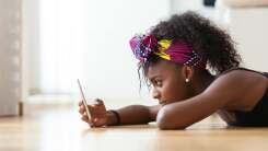 Woman lying on floor, texting on smartphone