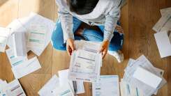 A woman viewed from overhead surrounded by paper bills