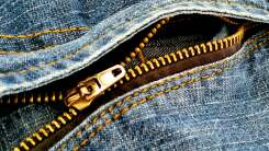 Close-up of a zipper on jeans that is separating.