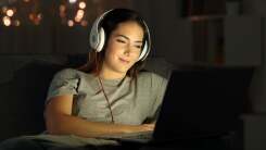 Student enjoying streaming on her laptop in a dark room.