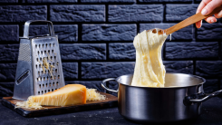 A wooden spoon scooping pomme aligot out of a pot.