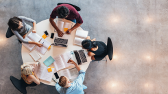 A group of young adults studying around a table, photographed from a bird's eye view