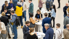 A crowd of people standing around tables at a networking event