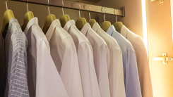 multiple pastel colored men's long-sleeved business shirts in closet with strip of lighting