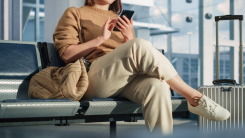 A woman looking at her phone, sitting at an airport gate