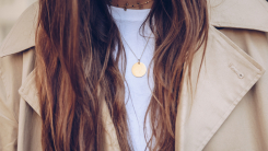 Woman with long hair wearing necklace and trench coat 