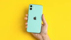 Hand holding mint-green iPhone on yellow background 