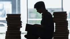 Silhouette of student studying amidst many books