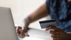 Woman typing credit card number into laptop