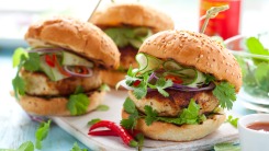 Three burgers on a cutting board