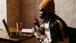 A college student studying with her laptop and taking notes in a cafe