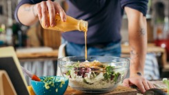 Man pouring salad dressing on a salad