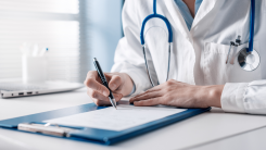 A doctor at a desk making notes in a patient's chart