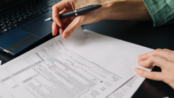 A close-up shot of a person filling out tax forms by hand