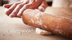 Hands rolling out a small ball of dough.