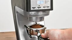 Someone using a Baratza Sette birr grinder to grind beans