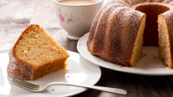 A slice of bundt cake on a plate next to the whole cake.