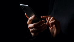 Hands holding smartphone on dark background