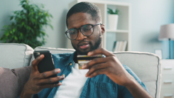 Man looking at phone and credit card.