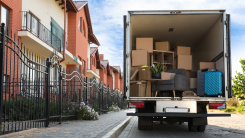 An moving truck parked on a street, with boxes stacked high in its trunk.