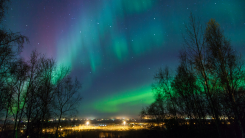 Northern lights and Big Dipper shine brightly over a city