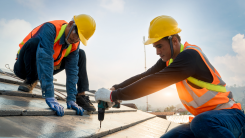 two male construction workers installing a roof of a house