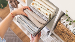 A person neatly folding clothes and placing them in an organized bin