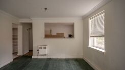 A plain, dated-looking basic apartment with white walls and dull carpet