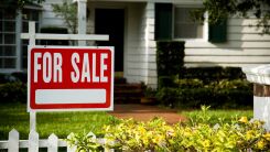 A for sale sign in front of a small home