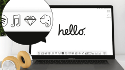 A MacBook on a white desk with headphones to its left. The MacBook's screen has a retro Apple wallpaper that reads, "Hello." The art for the wallpaper and all the icons in the dock use pixel art and mimic the retro look from classic Mac OS.