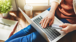 Woman typing credit card into laptop