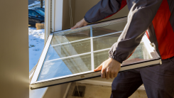 man taking a window out of a home