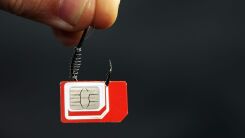 Fingertips holding a small hook with a SIM card attached to it