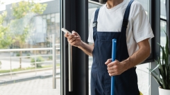 man holding phone next to window