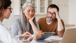 Financial advisor consulting mature middle-aged couple showing them debts