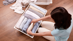 woman folding clothes and packing them away in a container