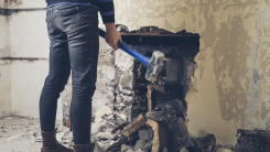 Person opening up an old fireplace in a Victorian house with a sledge hammer