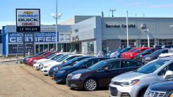 cars lined up at a car lot on a sunny day