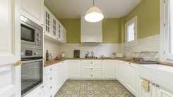 A renovated kitchen with a patterned tile floor, white cabinets, and green walls.