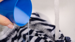 Person pouring detergent onto fabric