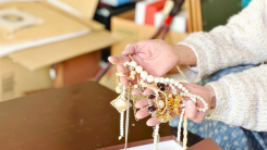 A woman's hands cradling a collection of necklaces against a background of moving boxes