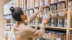 young woman buying cereals and grains in sustainable grocery store