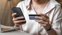 woman looking at a credit card and using phone to make a call