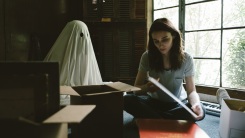 A ghost watches over a person in a still from A Ghost Story