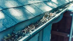 A photo of a metal rain gutter filled with leaves