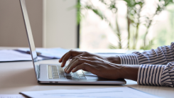 Hands typing on a keyboard in a home office