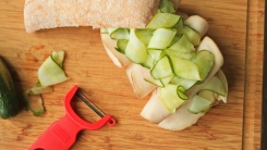 Close up of pickles on a sandwich on a cutting board.